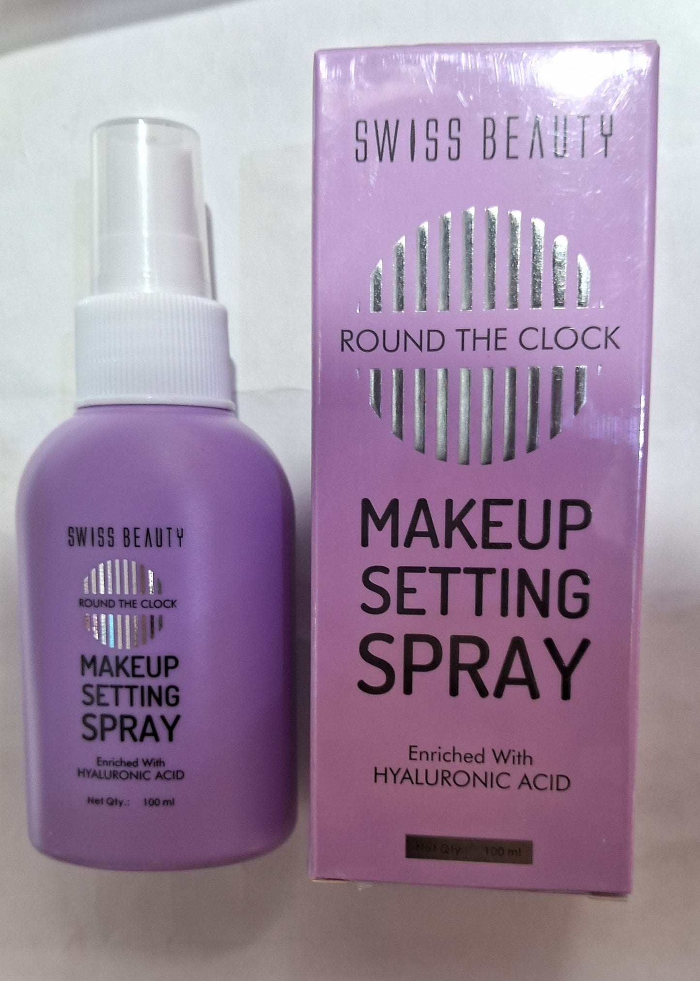 Makeup setting spray bottle and packaging on a surface